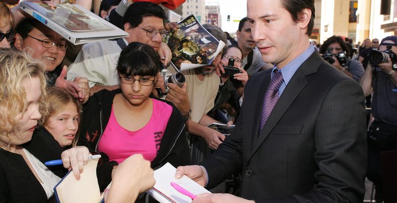 keanu reeves imbracat in costum ofera autografe fanilor