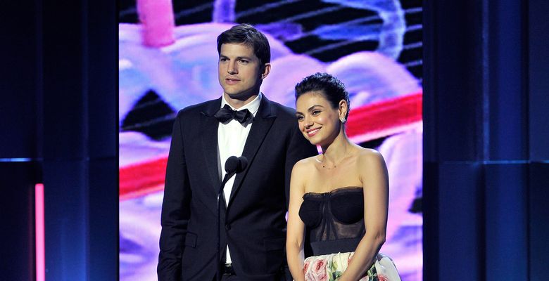ashton kutcher si mila kunis stau in fara unui microfon la un eveniment de gala de la hollywood