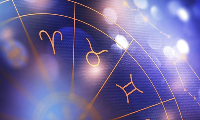 Astrology zodiac signs on a blue background with light reflections visible in the scene